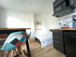 eine kleine Küche mit einem Schreibtisch und einem Bett in der Unterkunft Le Montgy - Studio tout confort à Royat National N1 in Royat