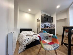 ein Schlafzimmer mit einem Bett und einem Stuhl sowie eine Küche in der Unterkunft Le Montgy - Studio tout confort à Royat National N1 in Royat
