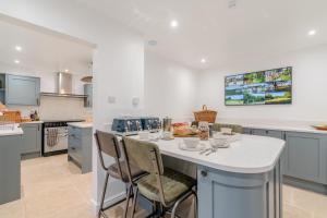 a kitchen with a white island with a table and chairs at Banbury Hill Farmhouse in Charlbury