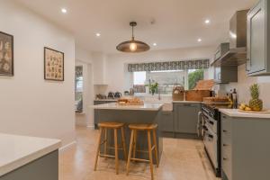 a kitchen with a large island and two stools at Banbury Hill Farmhouse in Charlbury