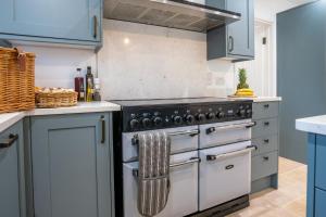 a kitchen with blue cabinets and a stove at Banbury Hill Farmhouse in Charlbury