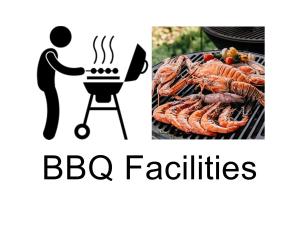 a man cooking food on a grill and a bbq facilities sign at Family Vacation Suites in Nagoya
