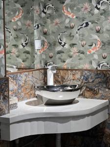 uma casa de banho com um lavatório e um papel de parede floral em WIND HOTEL em Shymkent