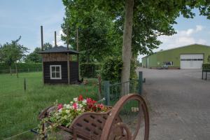 un banco de parque con flores junto a un edificio en De Dorsvloer, en Drimmelen