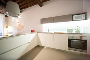 a kitchen with white cabinets and a sink and a stove at La Corticella Luxury Suite, with Terrace in Lucca