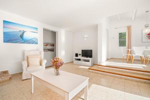 a living room with a white table and a tv at Villa San Cristobal by 3VILLAS in Binibeca