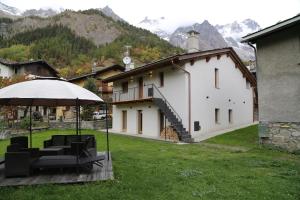 a house with a table and chairs and an umbrella at Appartamenti vista Monte Bianco Courmayeur-Entrèves in Entrèves