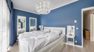 ein blaues Schlafzimmer mit einem großen Bett und einem Kronleuchter in der Unterkunft Apartamenty Sun & Snow Playa Baltis z sauną in Misdroy