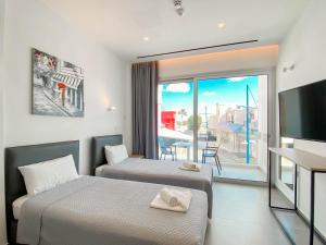 a hotel room with two beds and a large window at Caramela Luxury Apts in Ayia Napa