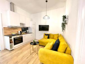 un salon avec un canapé jaune et une cuisine dans l'établissement Apartment Maximilian, à Vienne