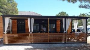 a wooden cabin with white drapes on it at M&M Mobile home in Privlaka