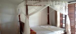 a bedroom with a canopy bed with a window at Surf Forever in Midigama