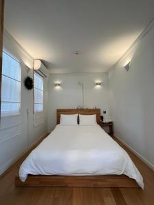 a bedroom with a bed with white sheets and a window at That space Jeju in Jeju