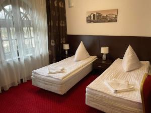 two beds in a hotel room with red carpet at Villa Stary Kalisz in Kalisz