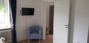 Pokój z niebieskim krzesłem i telewizorem na ścianie w obiekcie Löhner Glück Perfekte Kombination von Geschäftsreise und Familie w mieście Löhne