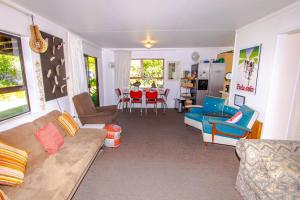 a living room with a couch and chairs and a table at Little Nikau - Tata Beach Holiday Home in Tata Beach