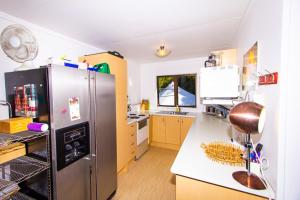 a kitchen with a stainless steel refrigerator in a room at Little Nikau - Tata Beach Holiday Home in Tata Beach