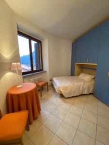een slaapkamer met een bed, een tafel en een raam bij Casa di borgo vista lago in Valsolda