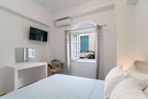 a white bedroom with a bed and a window at Mary's Suite in Naousa