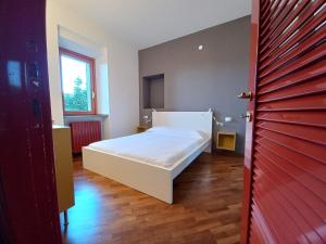 a bedroom with a white bed and a red door at Residenze La Madonnina in Vigatto