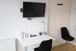 a white desk with two chairs and a tv on a wall at Motel Sindal in Sindal