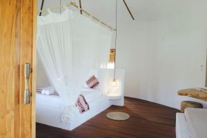a white room with a bed with curtains at Mana Eco Retreat in Kuta Lombok