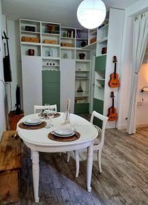 トリノにあるIncantevole appartamento a Torino!のギター付きの部屋に白いテーブルと椅子2脚