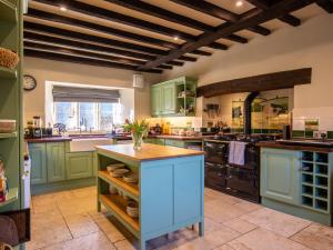 a large kitchen with green cabinets and a blue island at Green Farm House in Cirencester