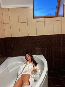 Una donna sdraiata nella vasca da bagno che parla al cellulare di New Continent a Bushtyno