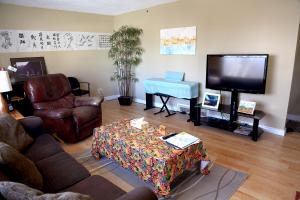 uma sala de estar com um sofá, uma mesa e uma televisão em Jenny Guest House em Yellowknife
