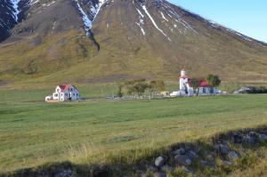a lighthouse in a field with a mountain in the background at Bólstaðarhlíð - Cottage (studio) in Bólstaðarhlíð