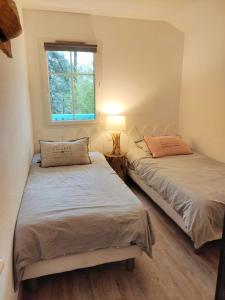 two beds in a room with a window at Un Nid dans la Pinède in Lacanau