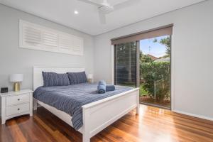 a white bedroom with a bed and a large window at Blue Beach House, 9 Cross Street, Port Macquarie in Port Macquarie