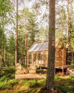 una cabaña en el bosque con dos sillas y un árbol en Nordic Island Hideout, 