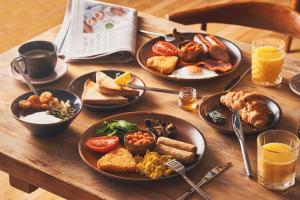 a wooden table with plates of breakfast food on it at Hope & Anchor in Hope Cove