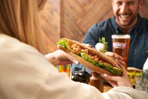 a woman holding a sandwich in front of a table at Hope & Anchor in Hope Cove