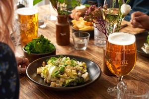 a table with a plate of food and two glasses of beer at Hope & Anchor in Hope Cove