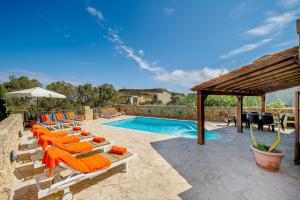 una piscina con sedie a sdraio arancioni e una piscina di Ta Gananz Holiday Home a Għasri