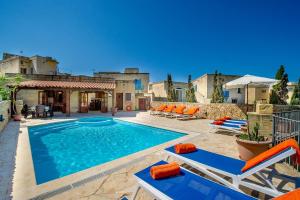 una piscina con sedie e una casa di Ta Gananz Holiday Home a Għasri