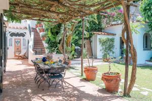 patio con tavolo e sedie sotto un pergolato di Villa Tragara by Elite Villas a Capri