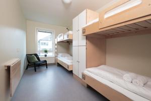 a bedroom with two bunk beds and a chair at Rumi Hostel in Trondheim