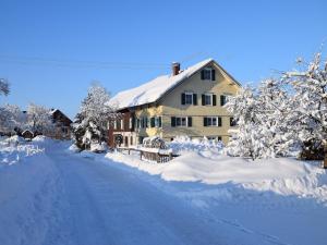 ein schneebedecktes Haus mit einer Straße davor in der Unterkunft Andreashof in Heimenkirch