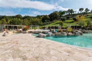 an outdoor swimming pool with rocks in a yard at Ovile in Roccalbegna