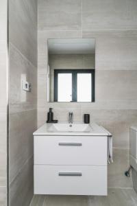 ein Badezimmer mit einem weißen Waschbecken und einem Spiegel in der Unterkunft Home2Book Sweet&Comfy Apartment Las Canteras in Las Palmas de Gran Canaria