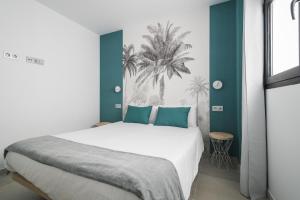 ein Schlafzimmer mit einem großen weißen Bett mit blauen Akzenten in der Unterkunft Home2Book Sweet&Comfy Apartment Las Canteras in Las Palmas de Gran Canaria