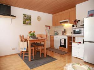 cocina con mesa, sillas y nevera en Andreashof, en Heimenkirch