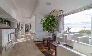 Una sala de estar con muebles blancos y una gran ventana. en Hotel Albahia Alicante, en Alicante