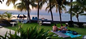 un grupo de personas sentadas en el césped cerca de la playa en 1000 Dream Bungalow en Lovina