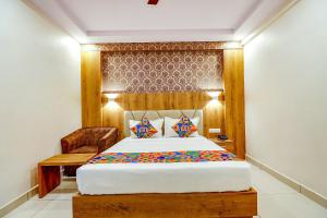a bedroom with a large bed and a chair at FabHotel Rotano Grand in Bangalore