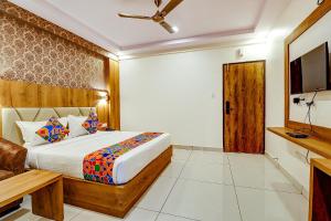 a bedroom with a bed and a television and a couch at FabHotel Rotano Grand in Bangalore